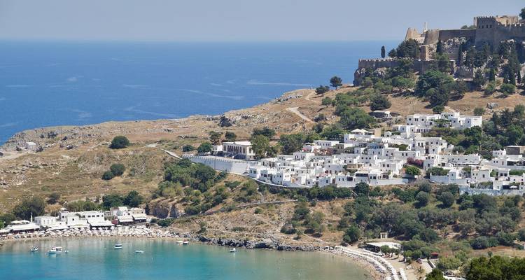 Vista panorámica de un pueblo costero con un castillo en una colina.