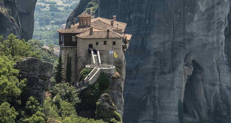 Ein Kloster mit einer griechischen Flagge, hoch oben auf einer Felsklippe in Kalabaka gelegen.