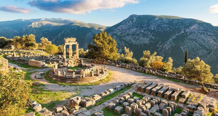 Ruinen des Apollontempels in Delphi vor einer bergigen Kulisse.