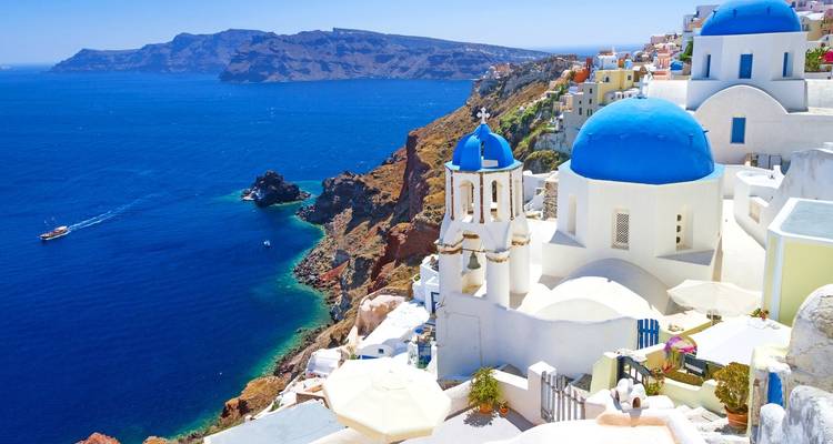 Santorinis ikonische blaue Kuppeln und weiße Gebäude mit Blick auf das Meer.