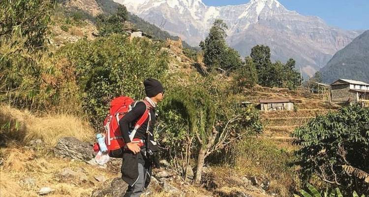 Persoon aan het wandelen met een rugzak in de buurt van terrasvormige heuvels en bergen.