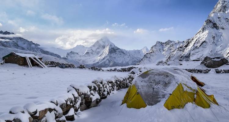 Snow-covered mountains with tents in the foreground.
