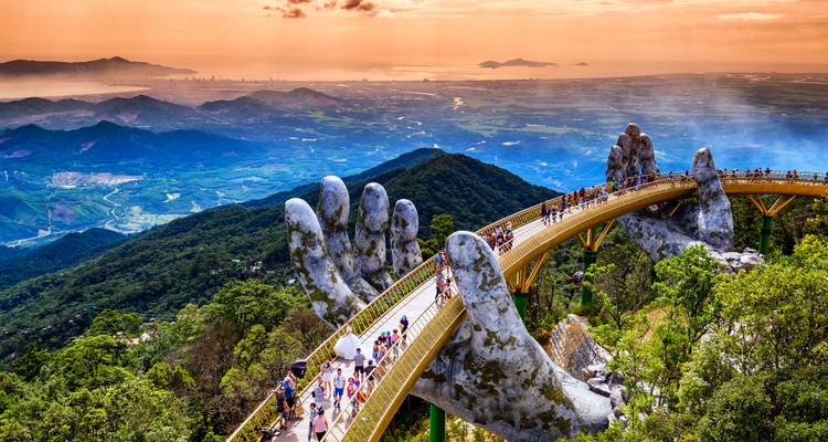 Puente Dorado sostenido por manos gigantes sobre un paisaje montañoso