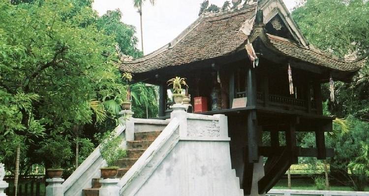 Structure de temple sur pilotis entourée d'arbres luxuriants.