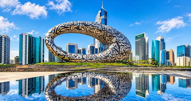 Musée futuriste de forme annulaire du Futur reflété parfaitement dans un bassin d'eau avec la skyline de Dubaï en arrière-plan.