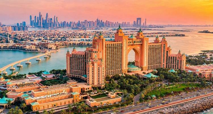 Le complexe Atlantis The Palm encadré par un coucher de soleil doré avec l'horizon de Dubaï en arrière-plan.