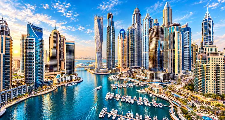 Panorámica aérea de Dubai Marina con rascacielos resplandecientes, vías acuáticas llenas de yates y el horizonte del golfo.