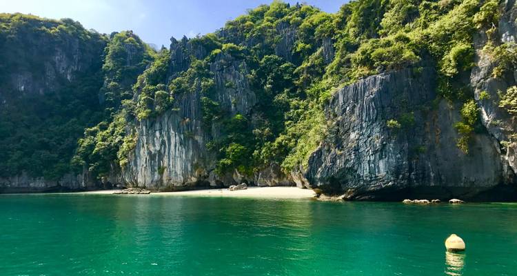 Anse de sable blanc isolée avec une eau émeraude sous de luxuriantes falaises calcaires