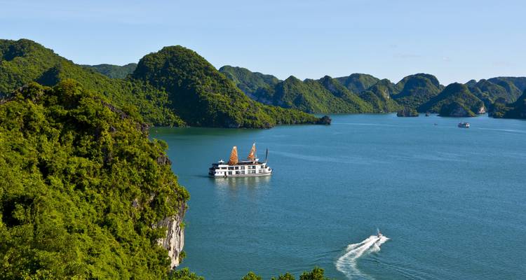 Vue panoramique de la baie depuis les hauteurs montrant des îles vertes et un bateau de croisière naviguant en contrebas