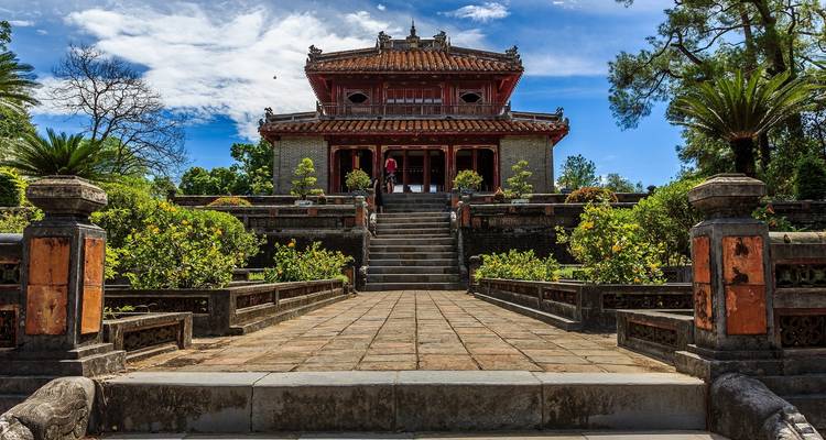 Historischer Grabpavillon umrahmt von gepflegten Gärten unter einem strahlend blauen Himmel