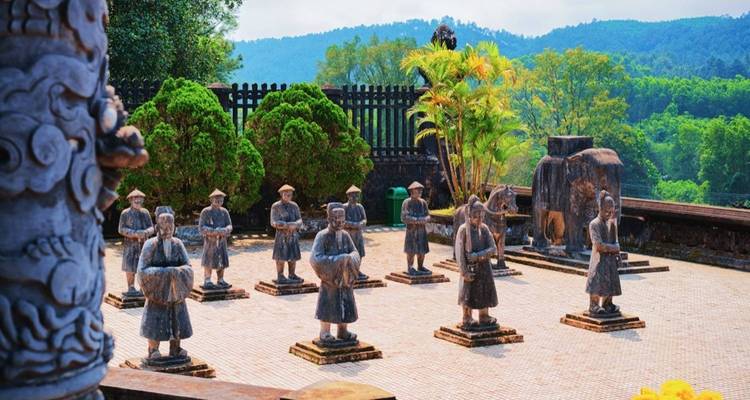 Innenhof mit steinernen Mandarin-Statuen an einem Kaisergrab vor einem bewaldeten Hügel