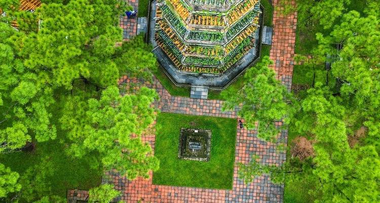 Luftaufnahme aus der Drohnenperspektive der achteckigen Thien Mu Pagode, die sich über gepflegte Gärten und Kiefern erhebt.