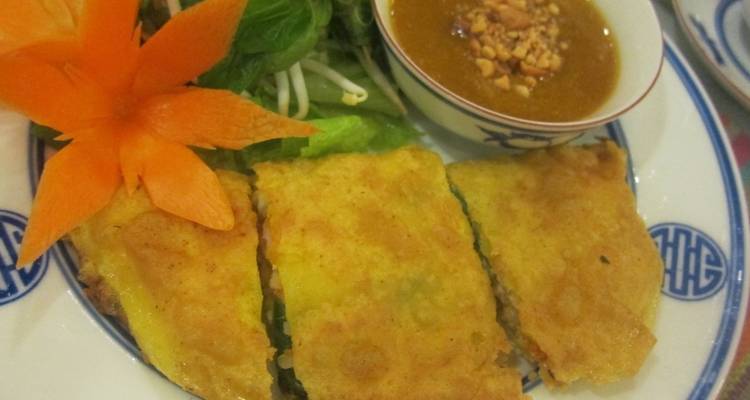 Nahaufnahme von knuspriger vietnamesischer Pfannkuchen serviert mit frischen Kräutern und Erdnuss-Dip-Sauce