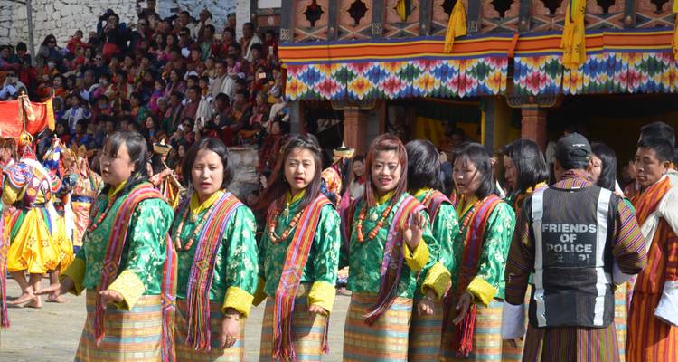Several women in traditional Bhutanese attire standing in a line at a festival.