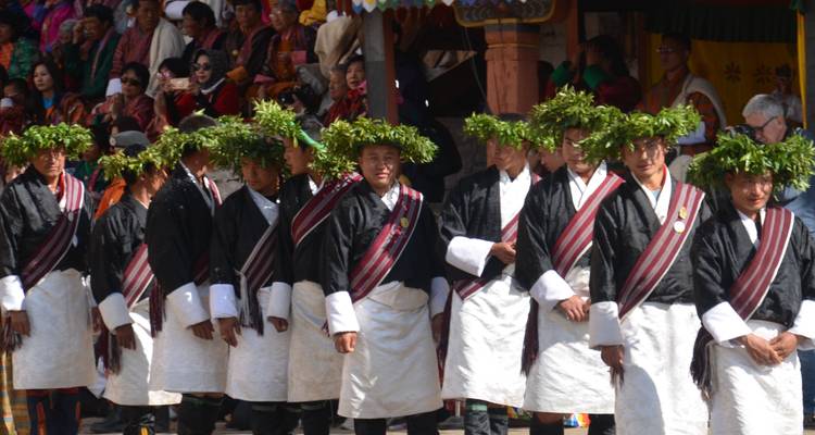 Men in traditional attire with garlands performing in a festival.