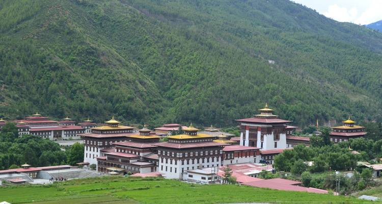 Panorama of a large traditional Bhutanese building with mountain backdrop.