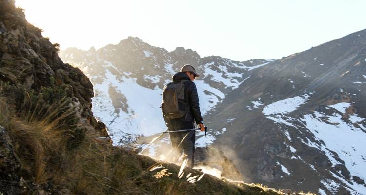 Eine Person, die wandert, mit schneebedeckten Bergen im Hintergrund.