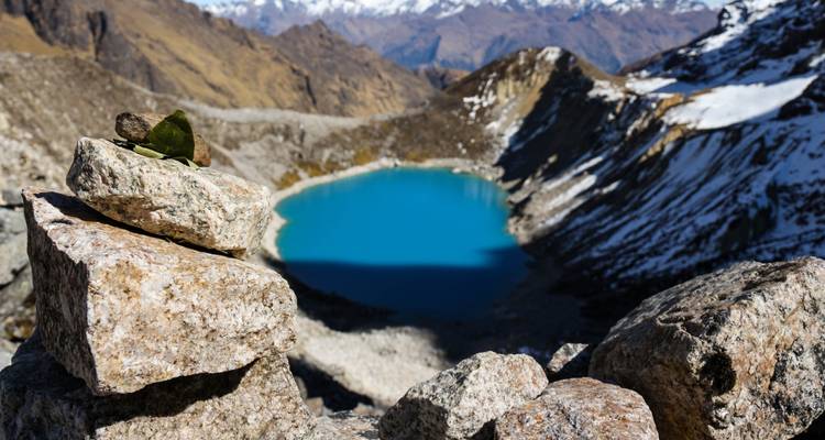 Ein Steinhaufen mit Blick auf einen blauen Bergsee.