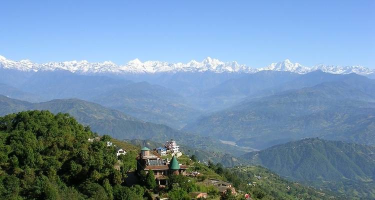 Weite landschaftliche Aussicht auf ein Dorf, umgeben von Bergen und Wäldern.