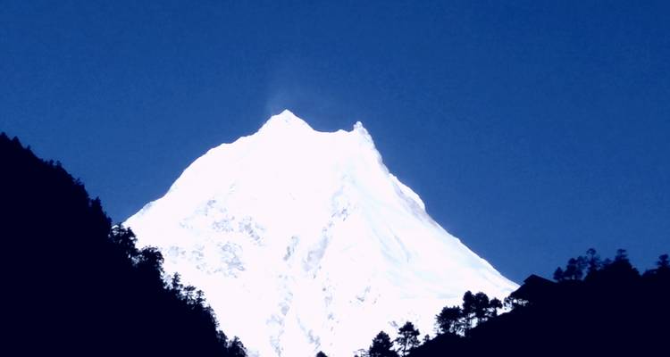 Besneeuwde bergtop met heldere blauwe lucht.