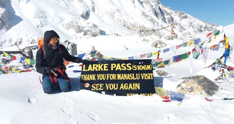 Persoon bij Larke Pass in besneeuwde bergen met gebedsvlaggen.