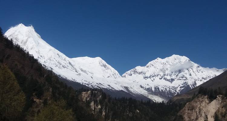 Besneeuwde bergtoppen tegen een heldere, strakblauwe hemel.