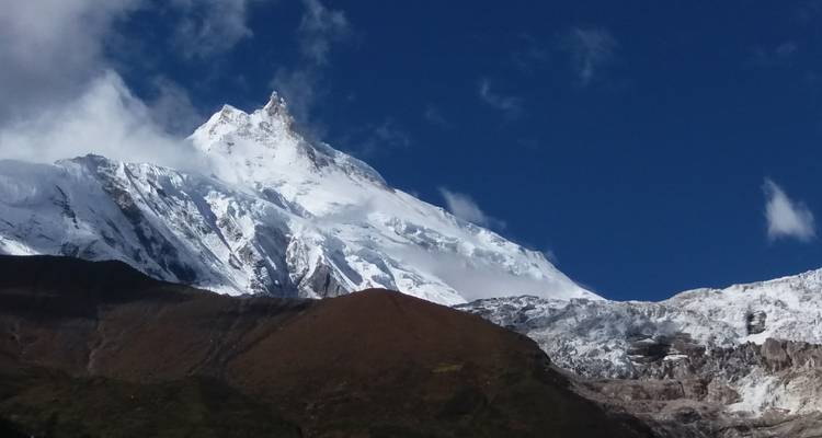 Besneeuwde bergtop tegen een blauwe lucht.