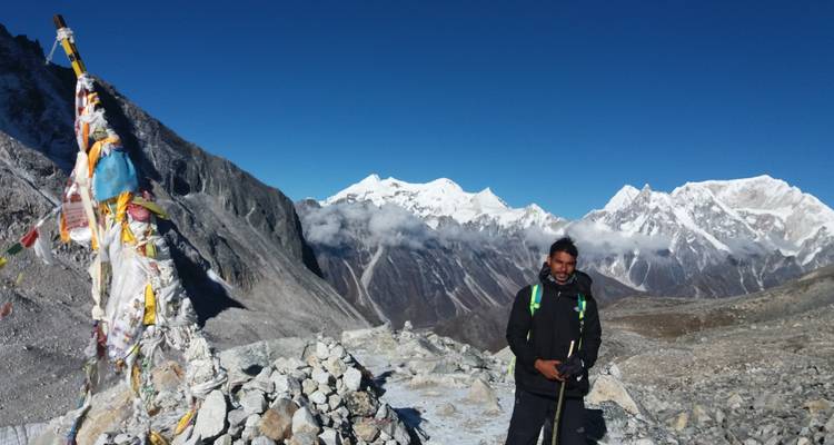 Persoon poseert met gebedsvlaggen in de bergen.