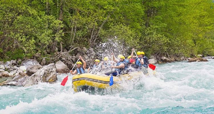 Rafting team navigating white-water rapid with splashes.