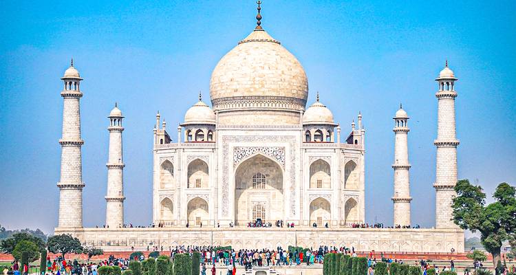 El icónico Taj Mahal con varios visitantes en el jardín.