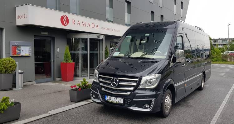 A tour van parked outside a hotel entrance.
