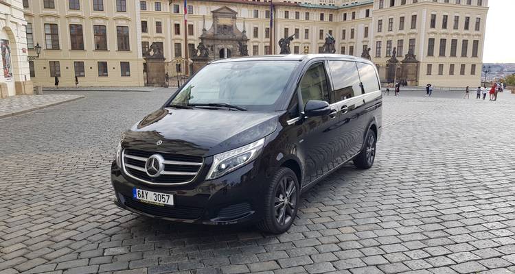 Black Mercedes van parked on cobblestone street.