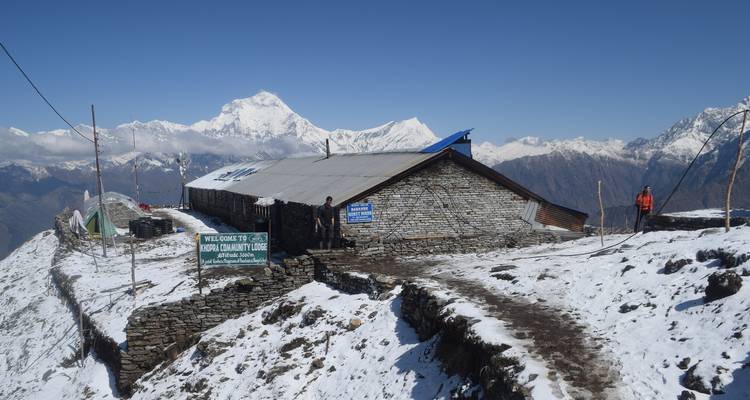Berghütte mit Himalaya-Kulisse und verschneitem Wanderweg.