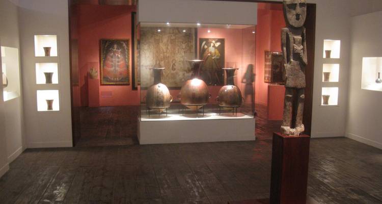 Sala de exhibición con artefactos precolombinos, cerámica y estatuas expuestas bajo una iluminación suave.