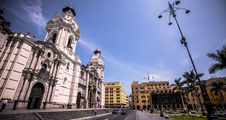 Las imponentes catedral y fachadas coloniales de Lima rodean la Plaza de Armas bajo un cielo azul brillante.