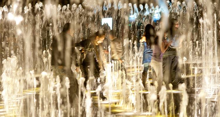 Los visitantes juegan entre los altos chorros de agua iluminados en el Circuito Mágico del Agua de Lima por la noche.