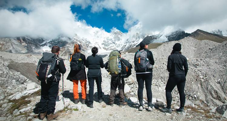 Trekking-Gruppe steht den schneebedeckten Himalaya-Gipfeln und Gletschern unter einem strahlend blauen Himmel gegenüber