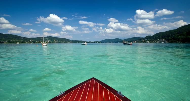 Boat bow over a clear lake with hills in the background.