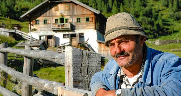 Portrait of a man with a mountain chalet in the background.
