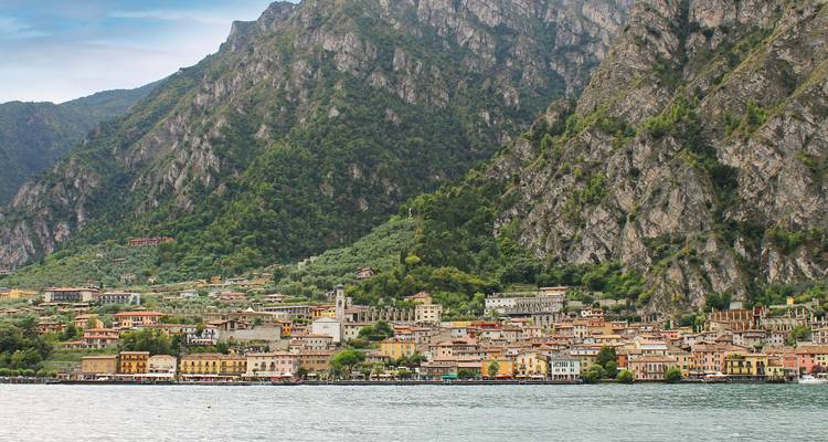 Colorful lakeside town lies at the foot of steep rocky mountains along a tranquil lake.