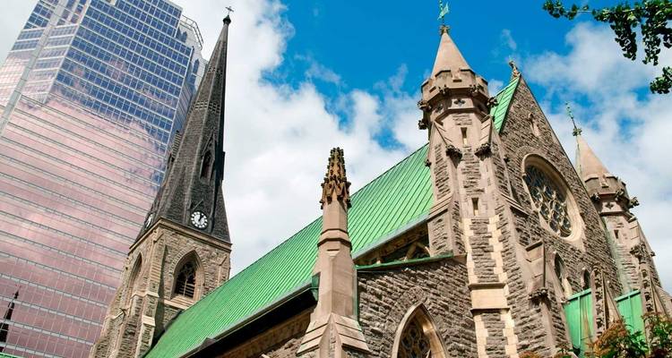 Contraste entre une église historique en pierre avec toit en cuivre vert et un gratte-ciel moderne en verre