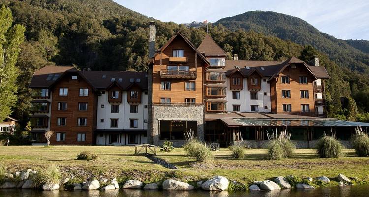 Un gran hotel situado contra una ladera boscosa.