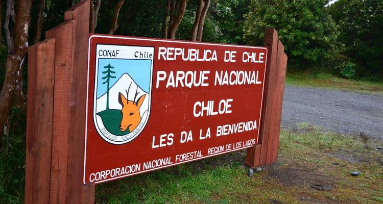 Cartel de bienvenida de parque nacional con fondo de bosque.