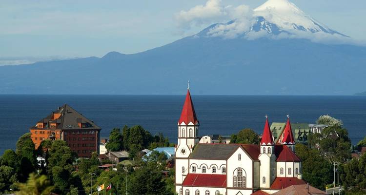 Una encantadora iglesia de techo rojo con un telón de fondo montañoso.