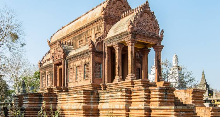 Ornate red sandstone temple pavilion standing on a tiered base under clear blue skies.