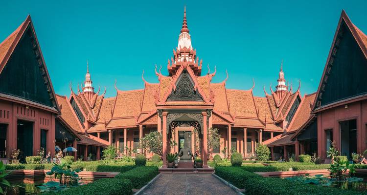 Symmetrical façade of the National Museum of Cambodia with red Khmer roofs and lush courtyards.