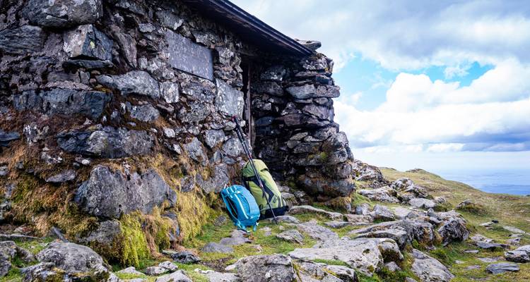 Stenen schuilplaats met wandelrugzakken in een bergachtig gebied.