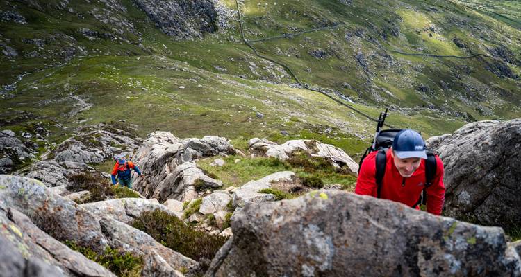 Twee wandelaars die klimmen op rotsachtig terrein.