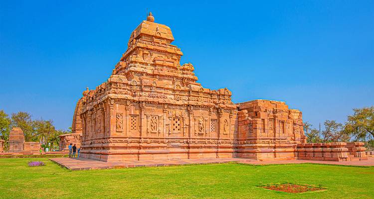 Temple ancien avec sculptures, environnement herbeux.