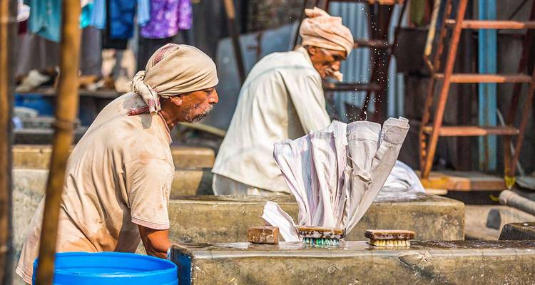 Des hommes lavant des vêtements dans une laverie en plein air.